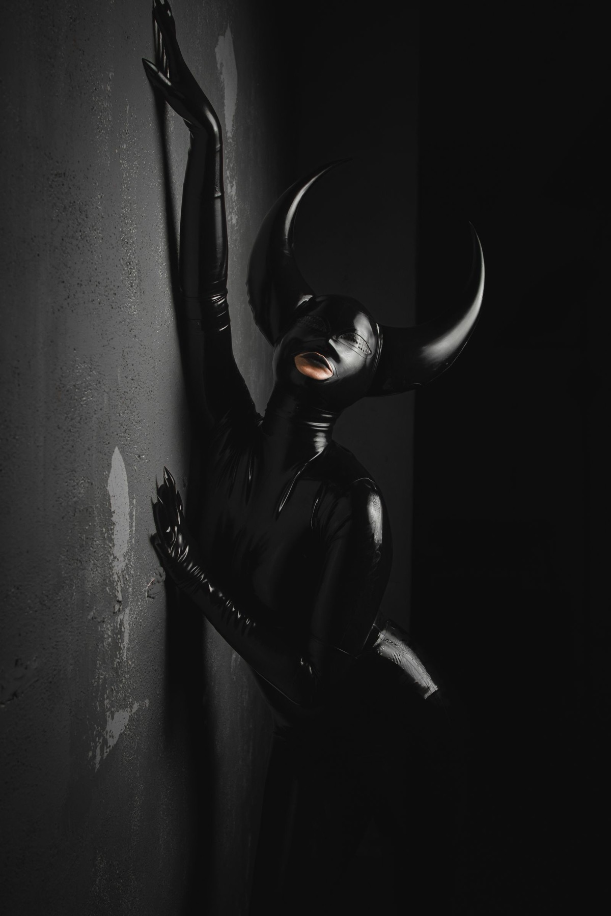 Person in schwarzem Latex-Outfit mit Maske und langen Handschuhen